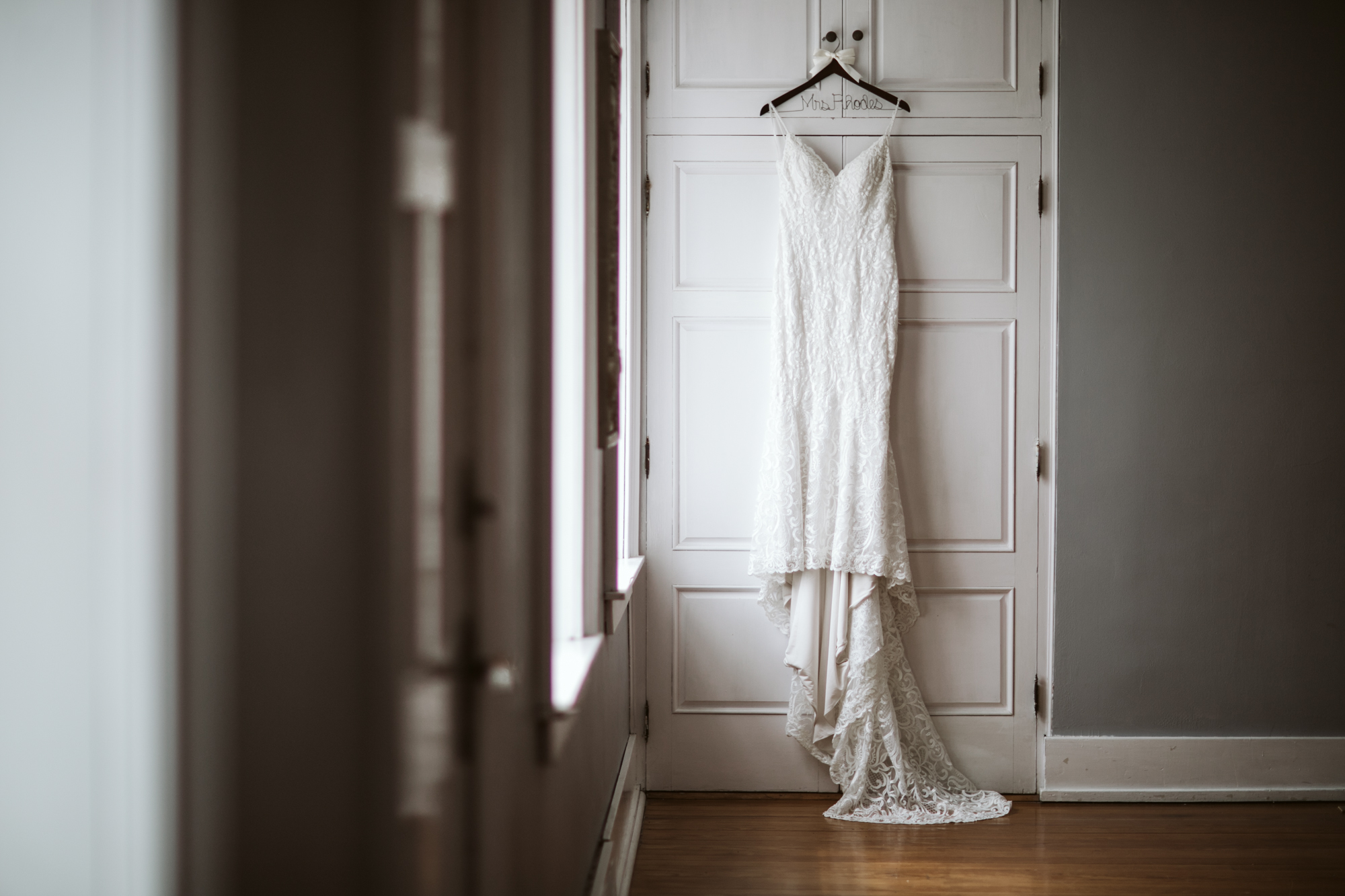 Wedding dress hung beside a window in the Stone House of St Charles