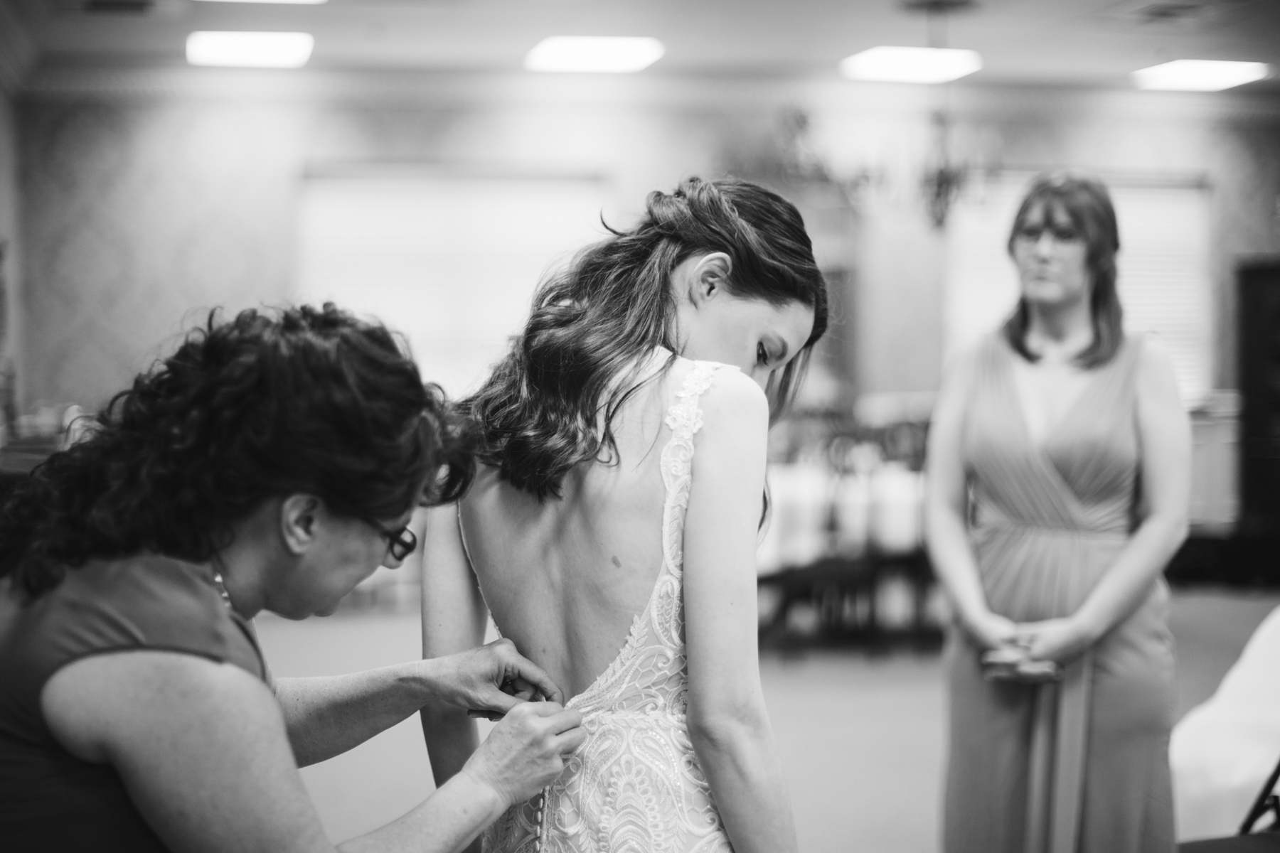 mother helping bride put on her dress at a rainy summer wedding at brentwood hills church in Nashville, tennessee