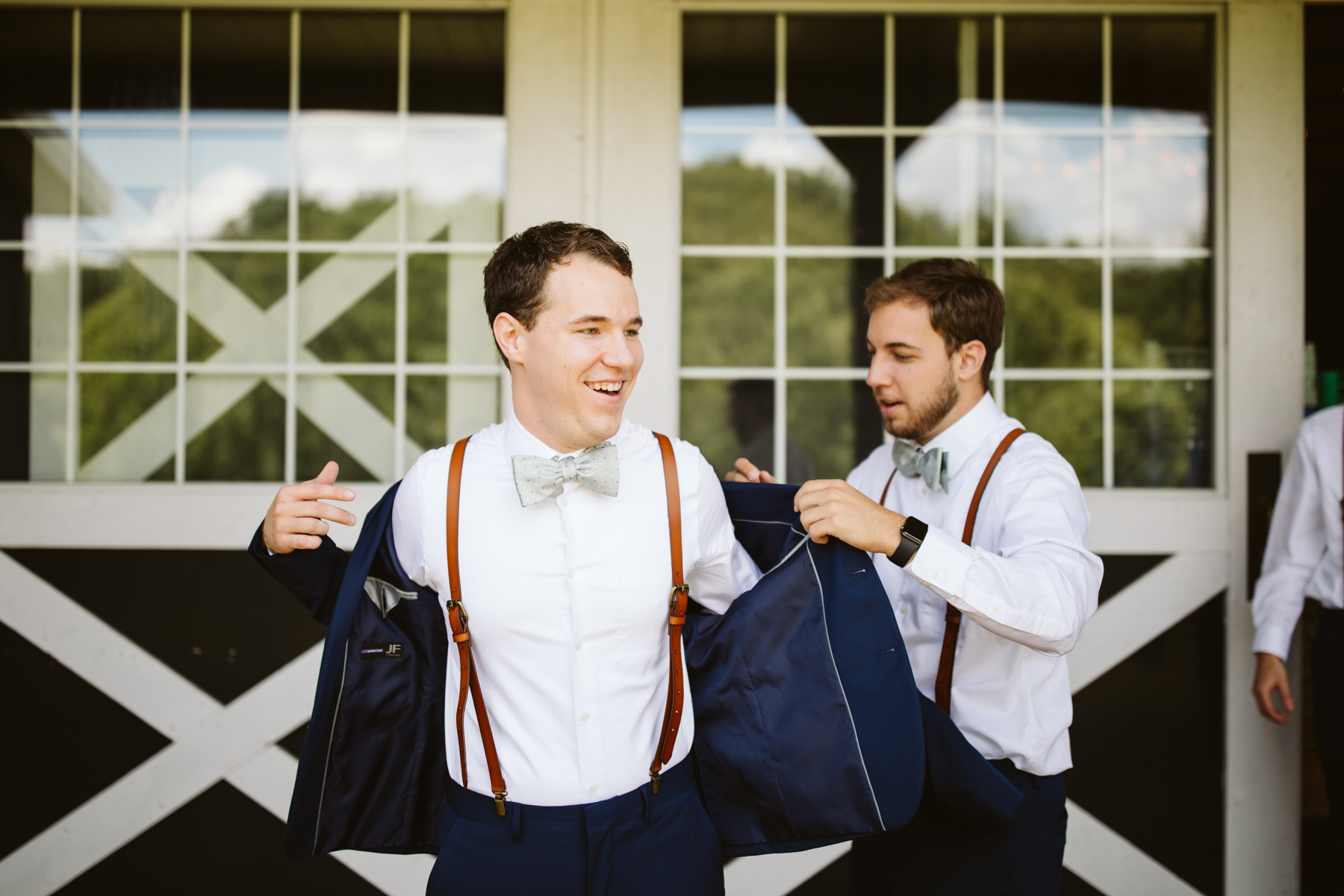 Groom putting on his jacket before a stables at strawberry creek wedding in Knoxville, tennessee