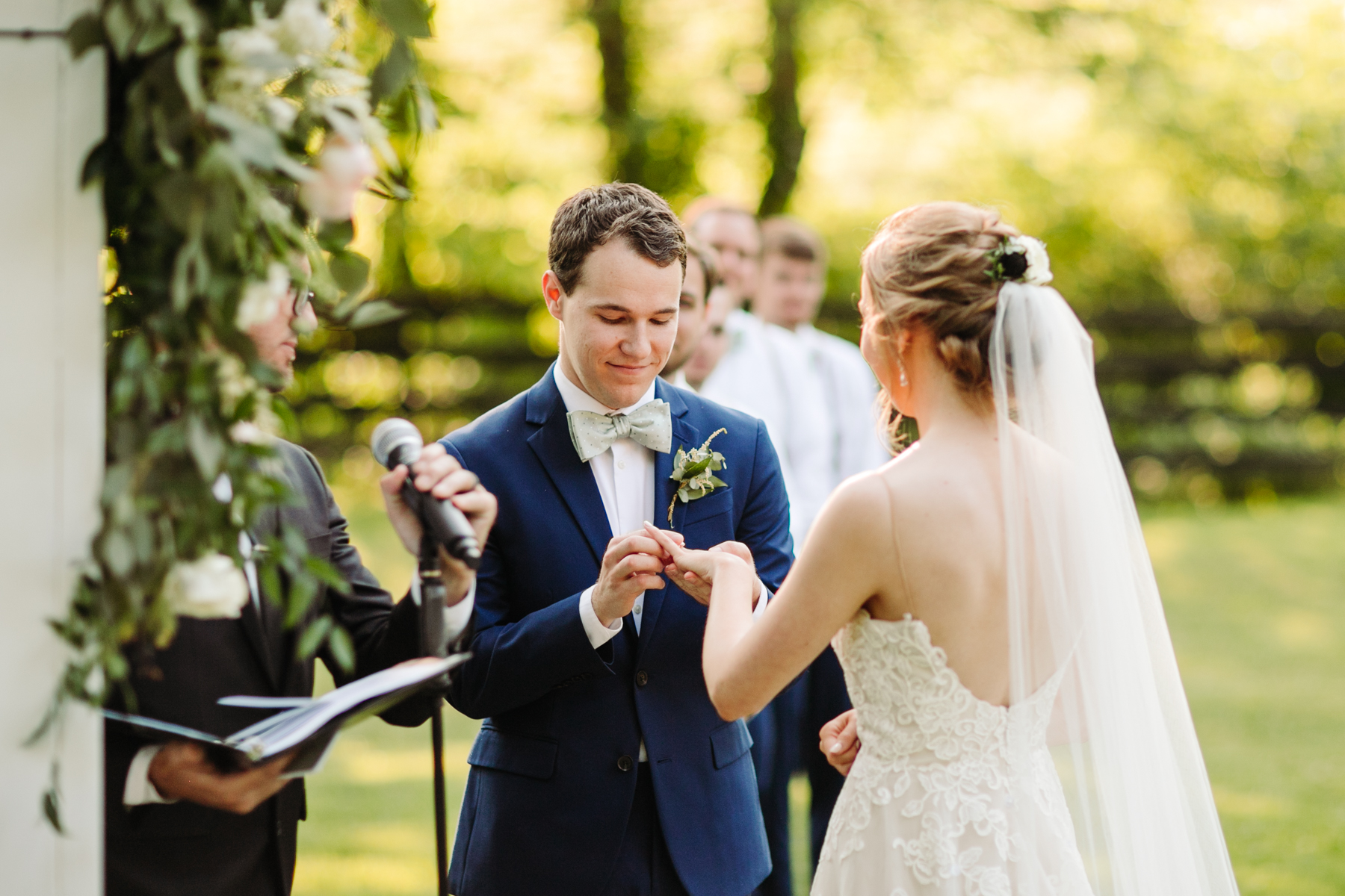 Groom puts a ring on his bride's finger at a stables at strawberry creek wedding in knoxville, tennessee