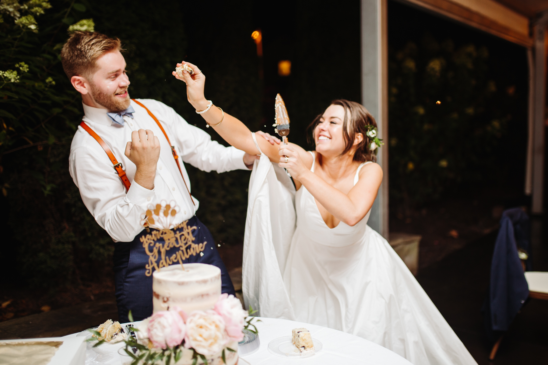 bride and groom smashing cake on each other during a reception of a Sunny summer wedding at Dara's Garden in Knoxville, Tennessee