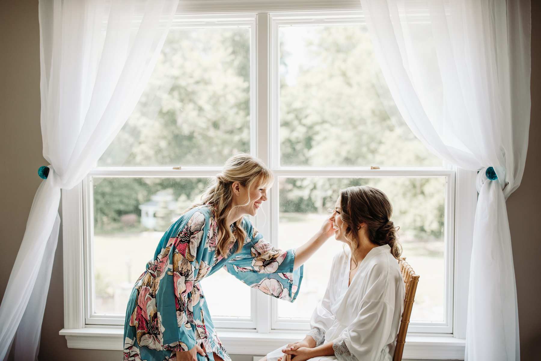 bridesmaid helping bride fix her makeup before a Sunny summer wedding at Dara's Garden in Knoxville, Tennessee 