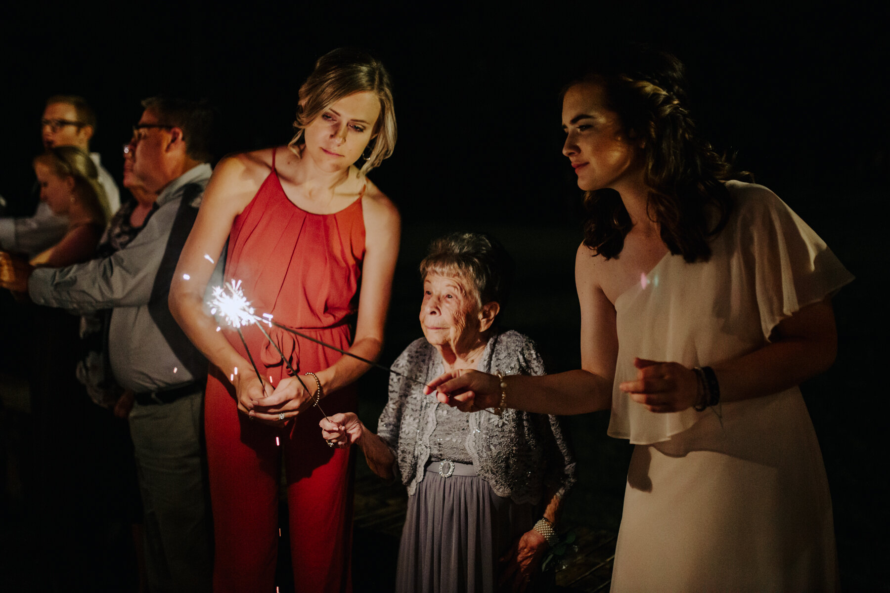 grandmother of the groom lighting sparklers at a sunny outdoor wedding at hunter valley farms in knoxville tennessee