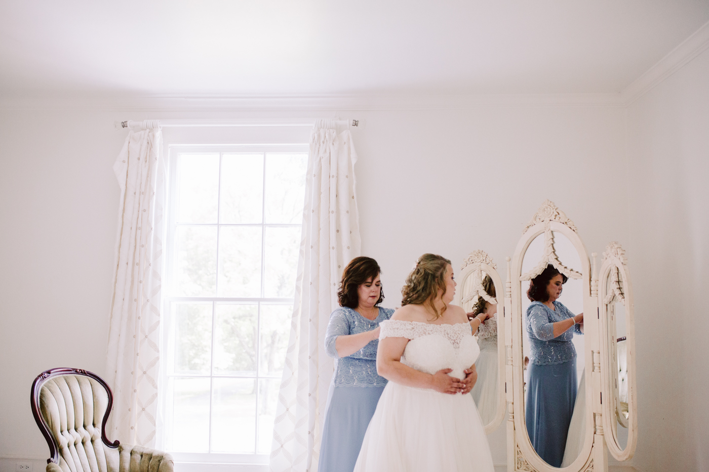 Bride putting on her dress at sunny summer wedding at the venue at twin oaks in tennessee